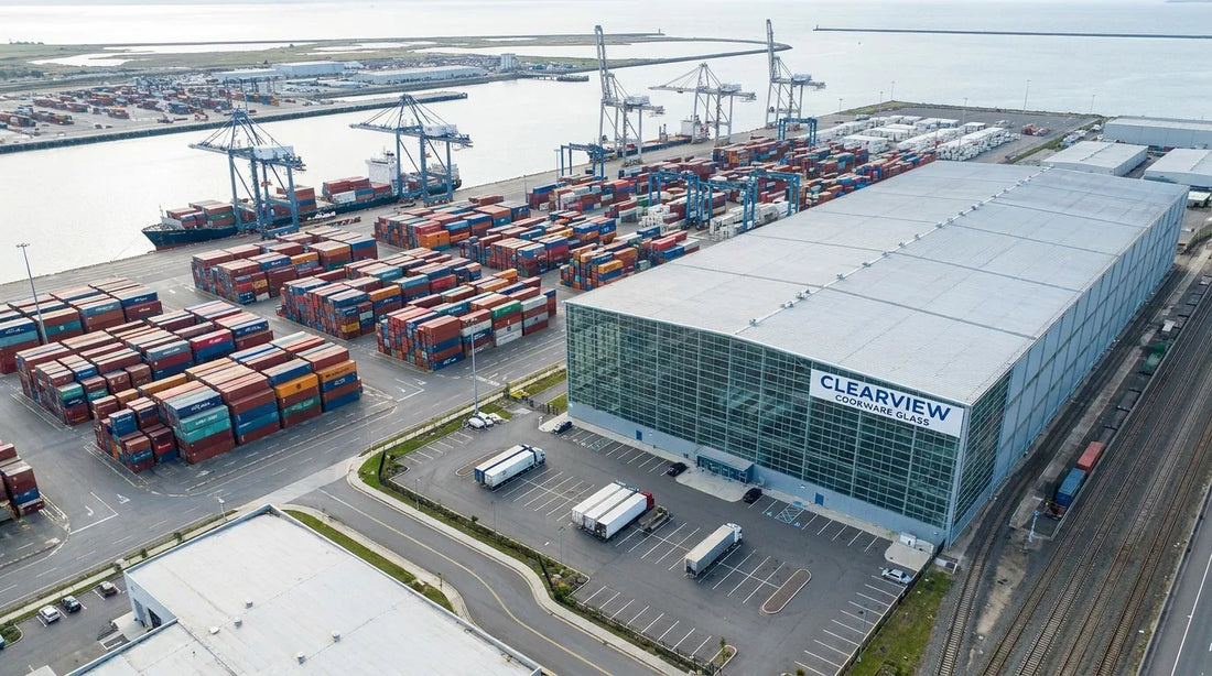 Aerial view of shipping containers and factory warehouse illustrating the FOB cost stack for tempered glass cookware lids from a China factory